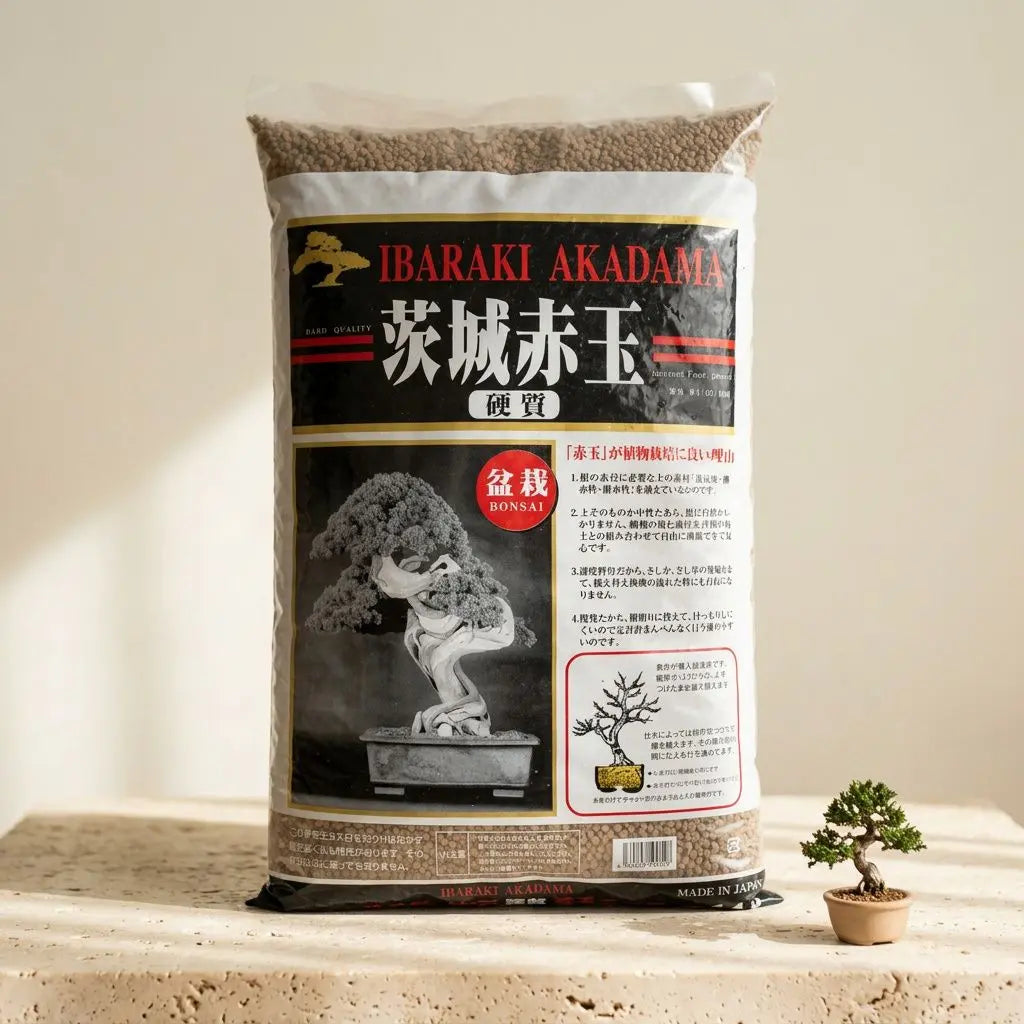 Sac d'akadama Ibaraki 14L grains moyens (2–6 mm) pour bonsaï, avec étiquette noir et rouge et petit bonsaï en pot à côté.